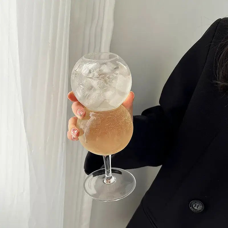 A clear two-tiered glass bubble ball glass with ice and amber drink from decorbites bubble ball set