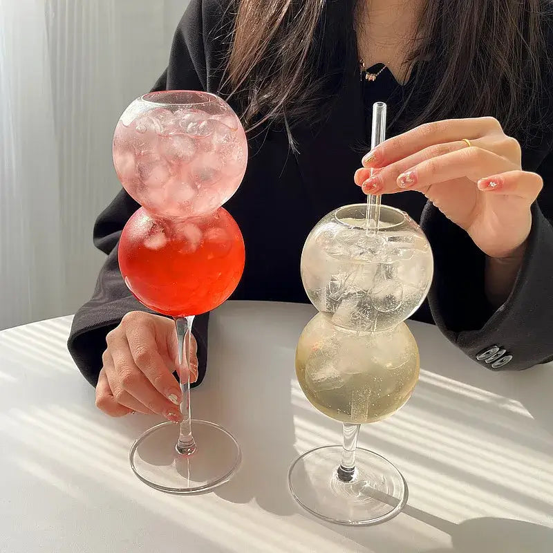 Two stacked glass bubble ball glasses from decorbites bubble ball set with pink layered and clear iced cocktails