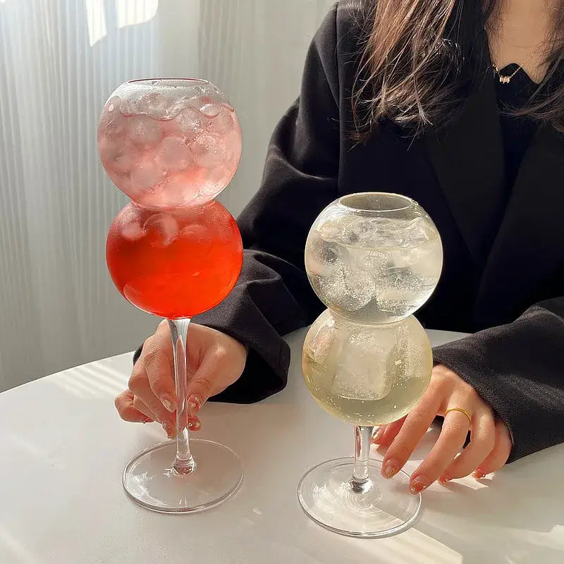 Two stacked glass bubble ball glasses from decorbites bubble set filled with pink layered and clear ice cocktails