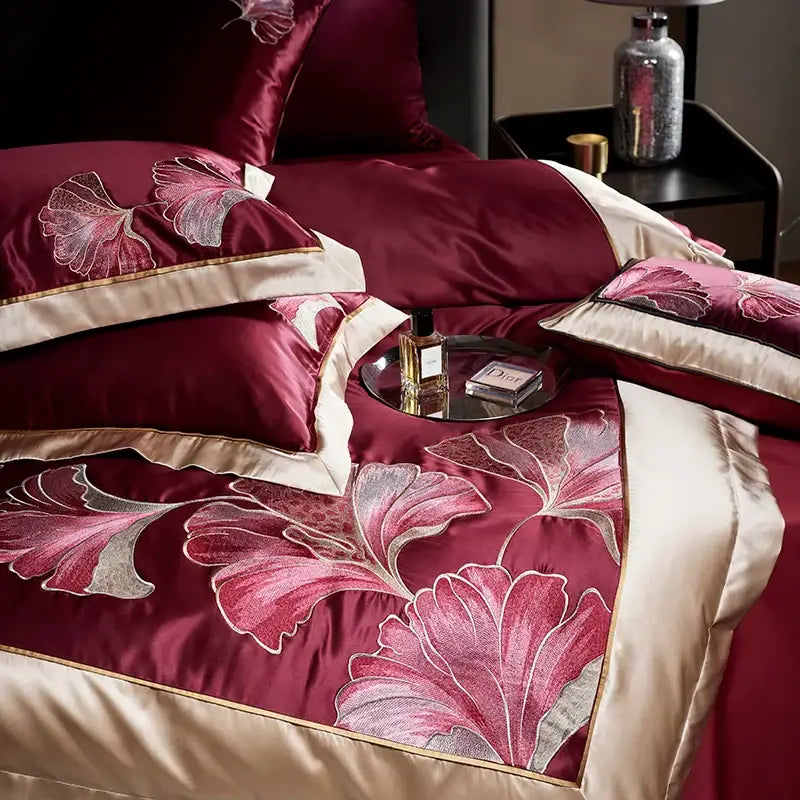 Deep burgundy satin egyptian cotton bedding set with intricate pink and silver ginkgo biloba embroidery and cream piping