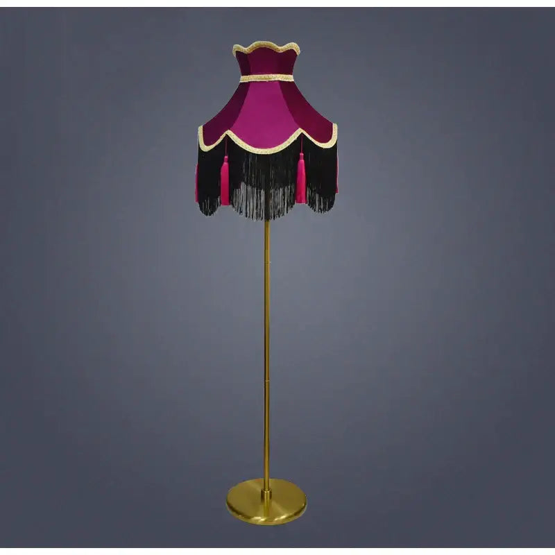 A vintage-style floor lamp with a burgundy wine red velvet scalloped lampshade featuring tassels and gold trim