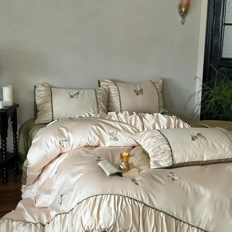 Cream-colored satin bedding set with decorbites butterfly embroidery and ruffled edges for elegant bedroom decor