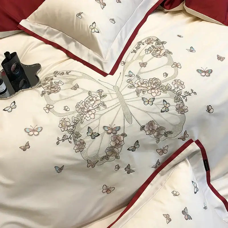 Cream-colored satin bedding set with butterfly flowers embroidery and bold red piping for elegant bedroom decorbites decor