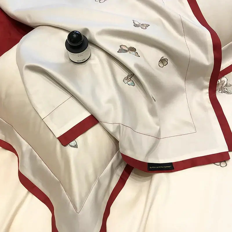 Cream-colored satin bedding set with decorbites butterfly flowers embroidery and bold red piping edges for bedroom decor