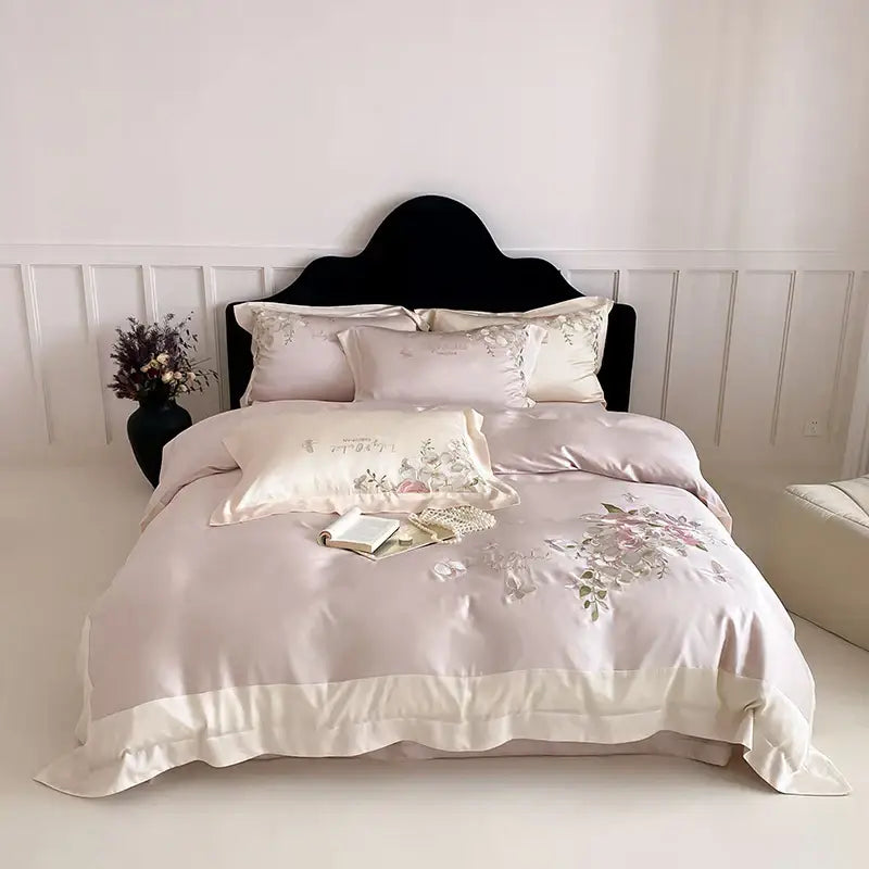 A blush pink satin bedding set with butterfly flowers embroidery and a cream ruffled hem for elegant decorbites decor