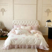 Ivory satin butterfly flowers lace bedding set with pink floral embroidery and ruffled edges on tufted white headboard