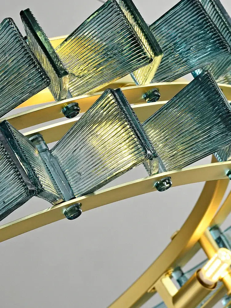A decorbites butterfly glass chandelier with translucent teal ridged panels on a polished brass frame for dining room lighting