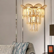 Gold finish crystal wall sconce with butterfly-inspired top and cascading teardrop crystals for bedroom lighting