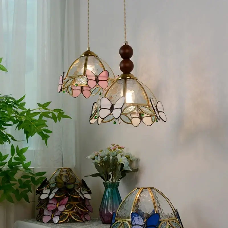 Two hanging decorbites butterfly tiffany glass pendant lights with pink white wings and green gemstone accents