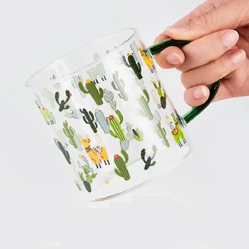 Clear glass tea milk cup with green handle featuring playful cactus and llama pattern decorbites cactus glass