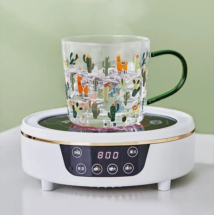 Clear glass tea milk cup with green handle and colorful cactus glass tea and llama pattern on white hot plate