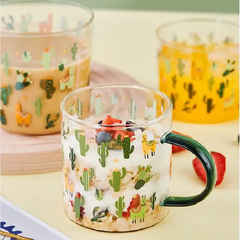 Clear glass tea milk cup with dark green handle featuring colorful cactus and llama pattern decorbites cactus glass
