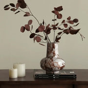 A calacatta red white and brown marble vase with rounded body holding dried eucalyptus branches for living room decor