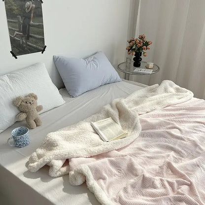 Soft white decorbites camellia jacquard lamb wool cozy blanket draped over bed with pink and light blue pillows