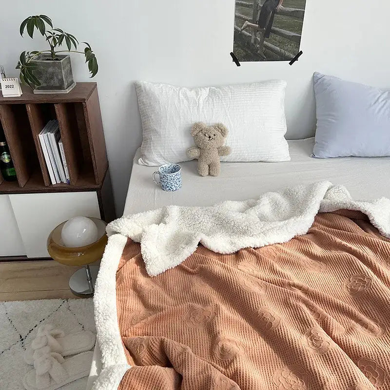 Soft peach-colored fleece decorbites camellia jacquard lamb wool cozy blanket with plush white border and floral embroidery