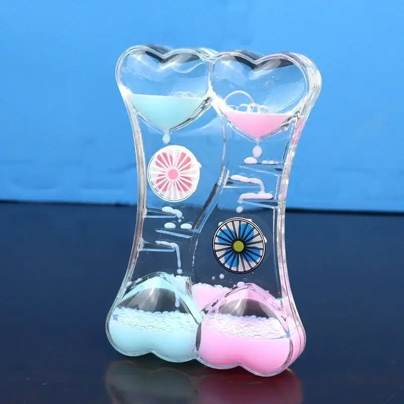 Clear glass liquid motion sand timer with blue and green heart-shaped chambers and decorative circular inserts for living room decor