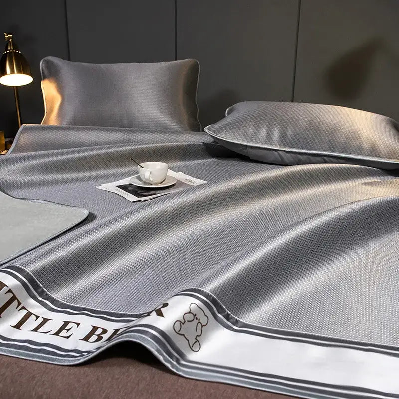 Gray satin-like carbon light cooling mat and pillowcase set with textured weave and embroidered bear decorbites carbon light