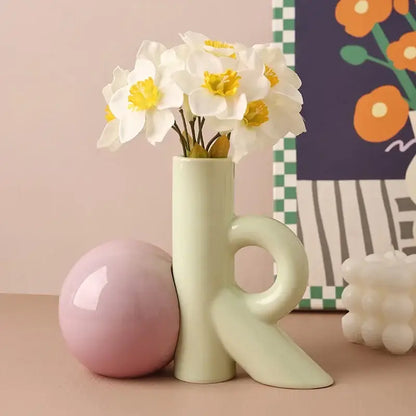 A sleek pale green abstract ceramic vase with integrated handle and angular base for decorbites cartoon abstract decor