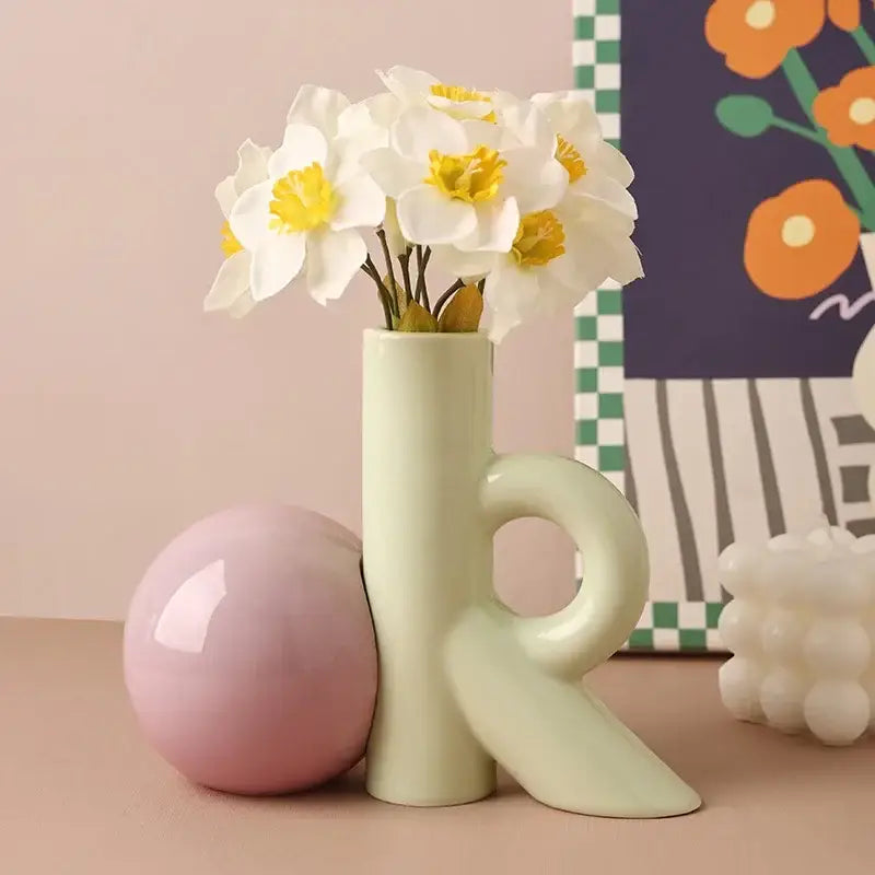 A sleek pale green abstract ceramic vase with integrated handle and angular base for decorbites cartoon abstract decor