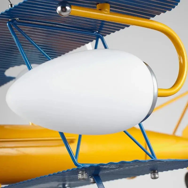 A white oval glass lampshade with silver rim on a blue and yellow decorbites cartoon aircraft ceiling fan