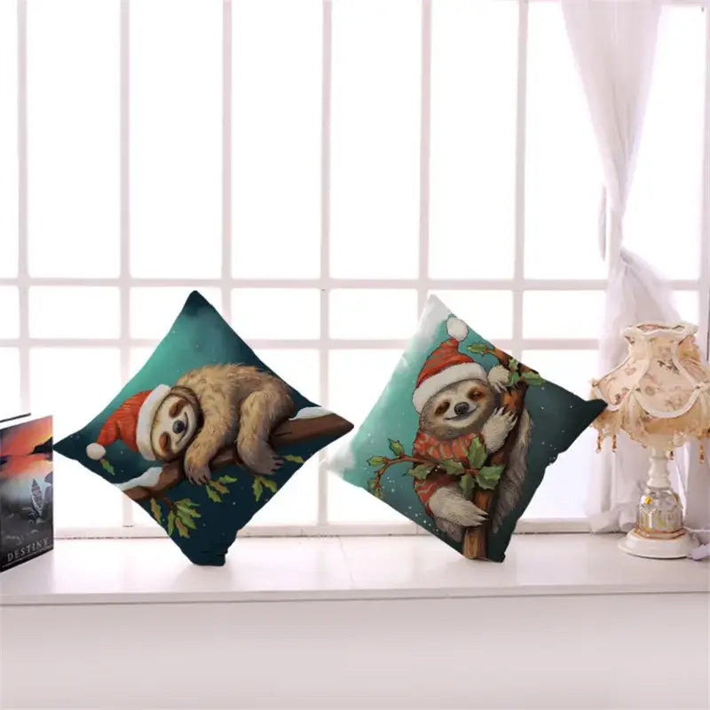 Two festive teal square cushion covers with cartoon sloths in christmas outfits from decorbites cartoon animal set