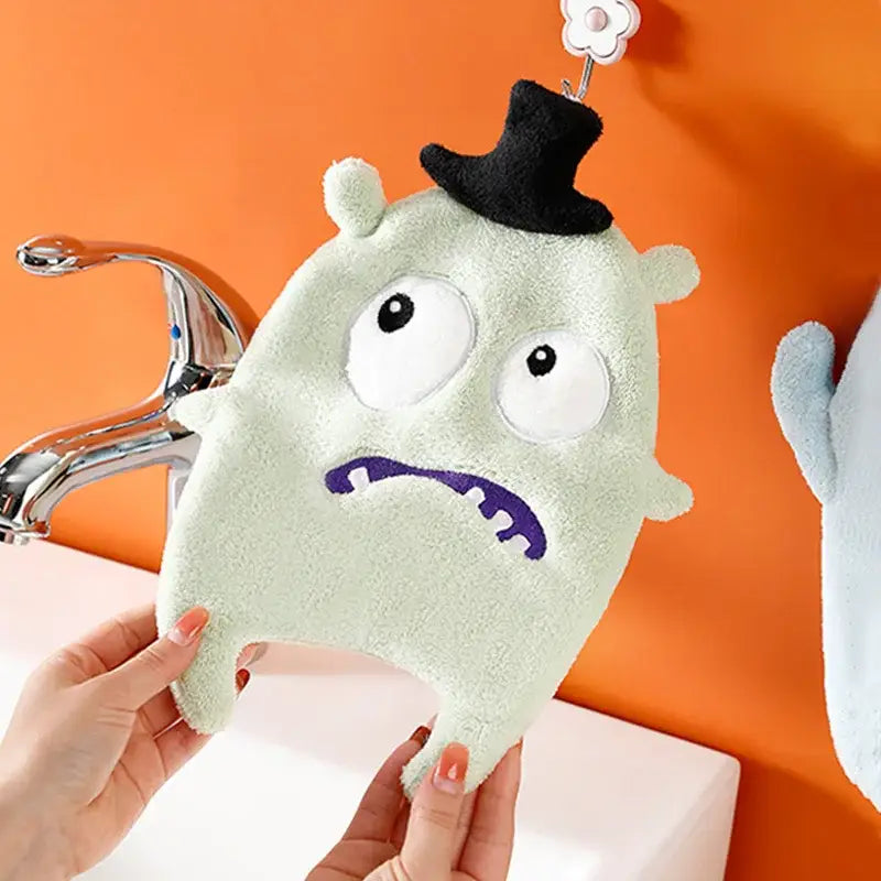 A light green plush zombie cartoon animal hand towel made of coral velvet with embroidered features and a black top hat
