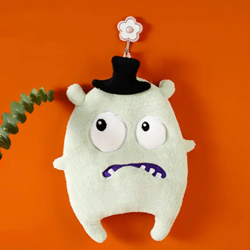A pale green coral velvet cartoon animal hand towel featuring a plush monster with oversized eyes and black top hat