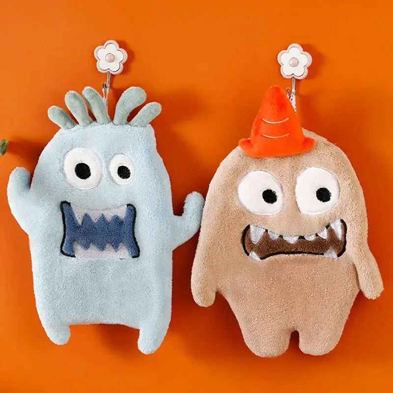 Two plush cartoon animal coral velvet monster hand towel hooks in light blue and beige with decorative hats for kitchen decor