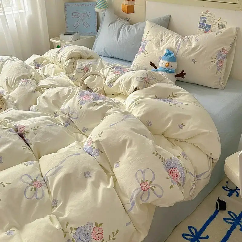 Cream-colored satin quilt cover set with cream quilt cover featuring floral and ribbon patterns in pink, lavender, and blue