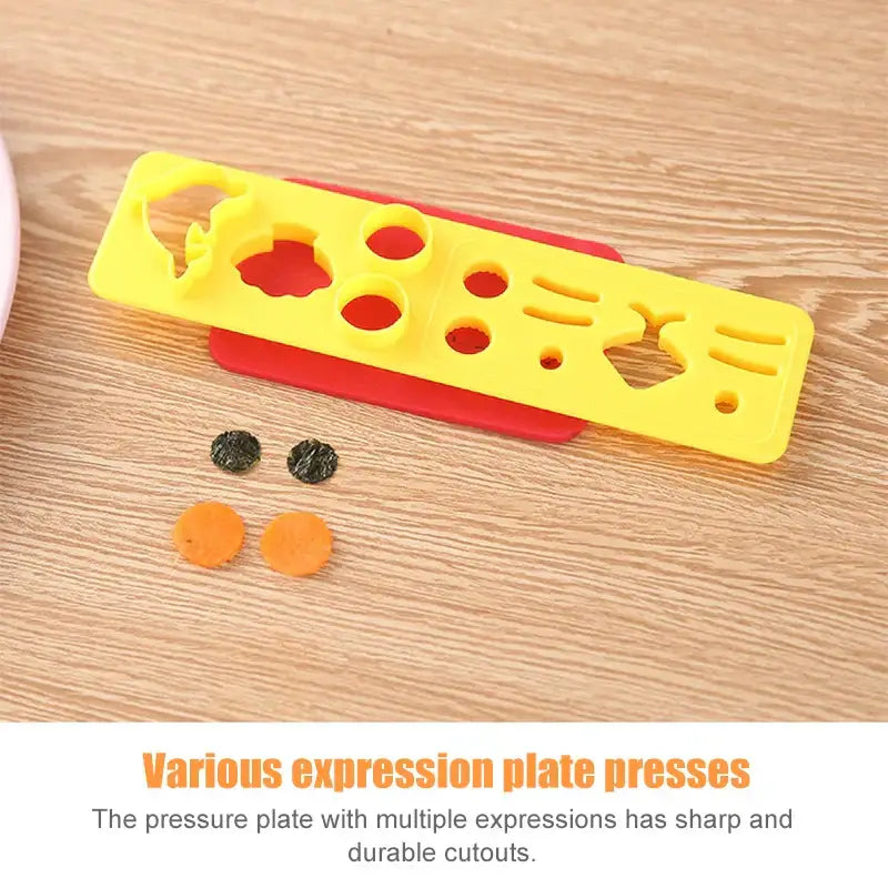 Bright yellow plastic sushi mold set with red base featuring multiple cutout expressions for shaping food