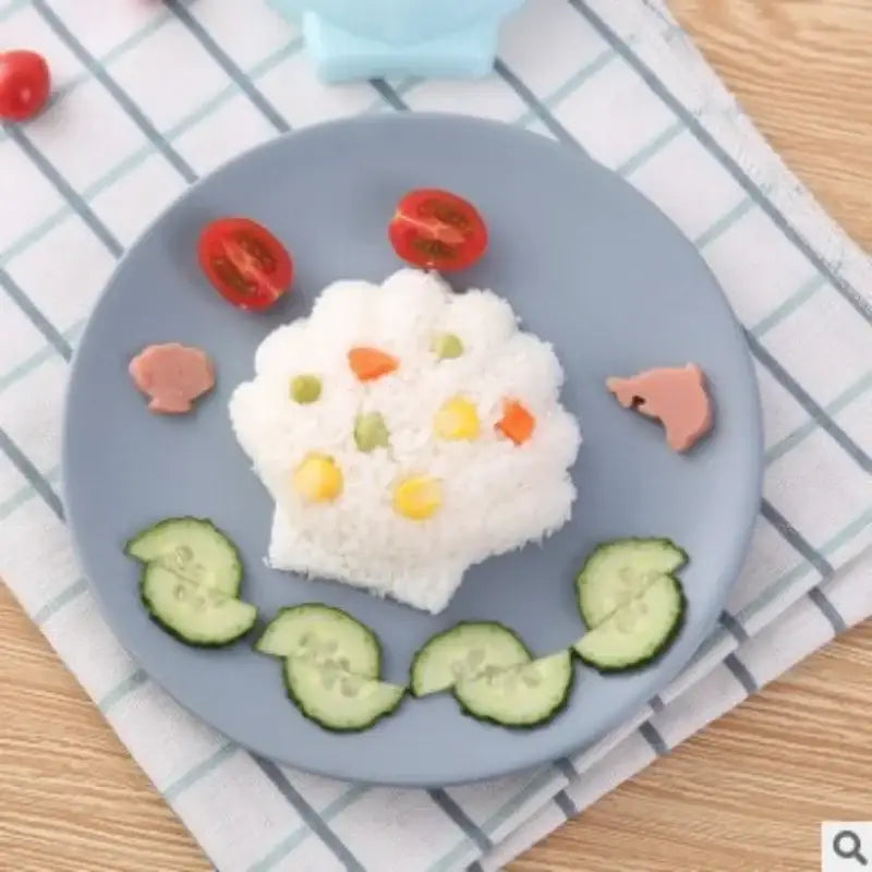 A light blue ceramic plate with glossy finish holds a smiling rice face made using a cartoon animal sushi mold set