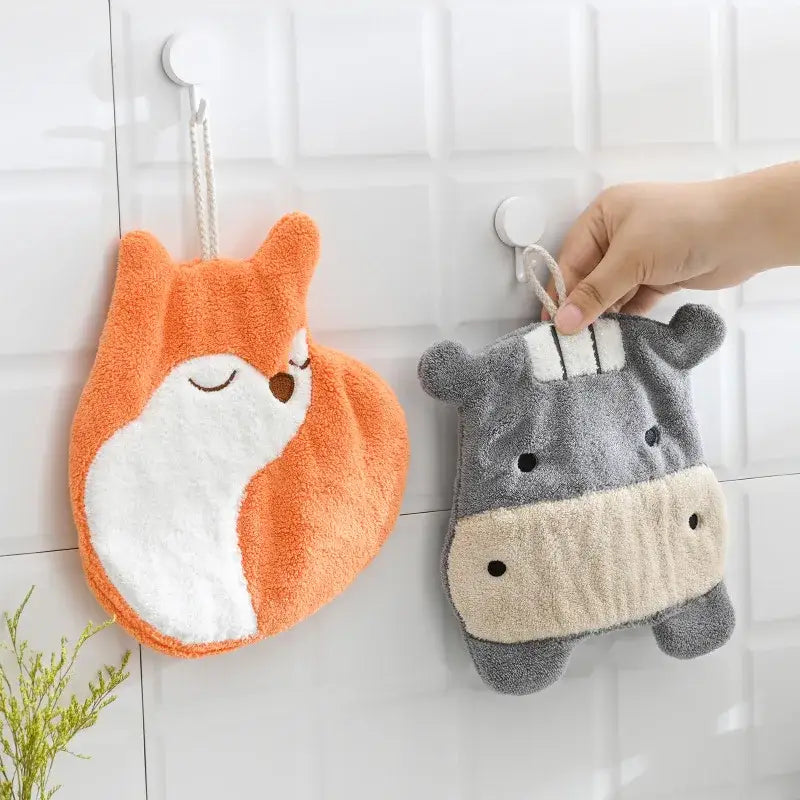 Orange and white plush fox hand towel made of coral velvet hanging next to gray hippo decorbites cartoon animals hand towel