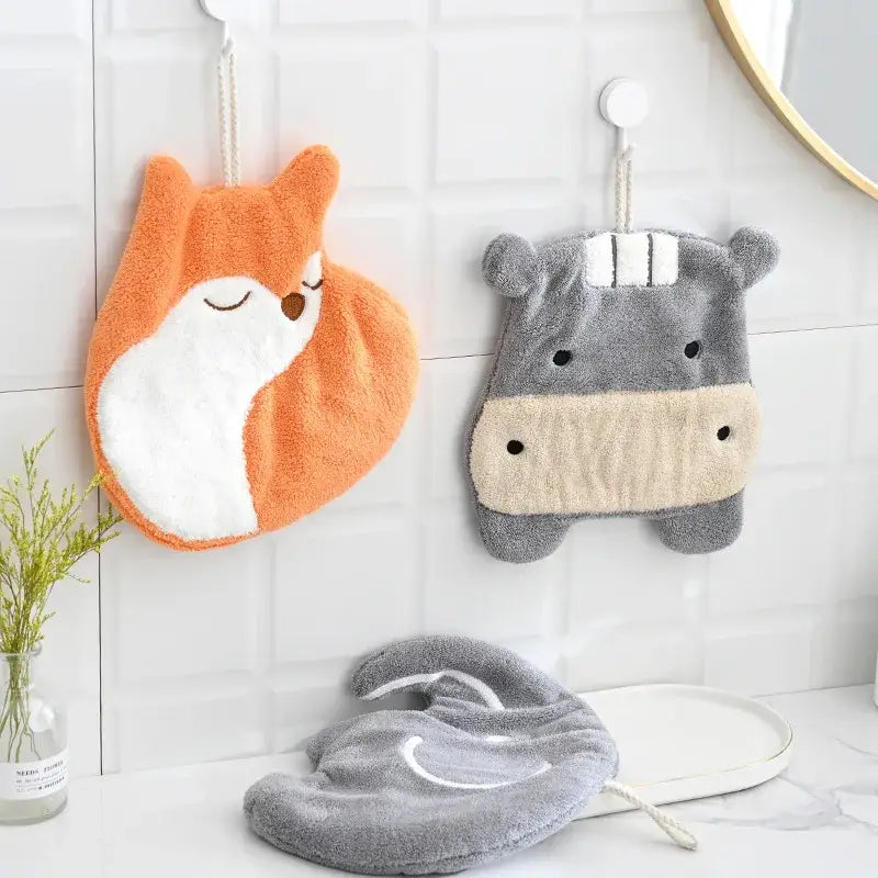 Orange and white plush fox hand towel hanging next to gray hippo coral velvet hand towel from decorbites cartoon animals