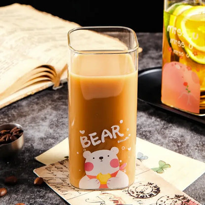 A clear glass coffee mug with a colorful cartoon bear pattern filled with an amber beverage