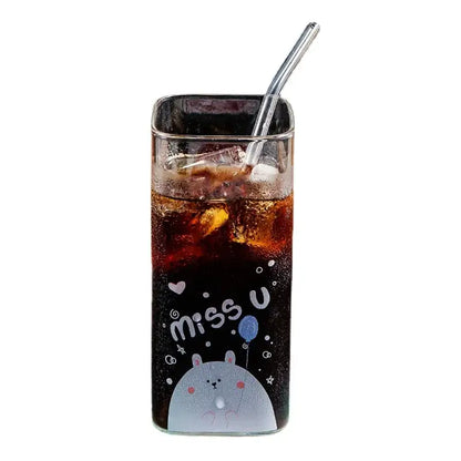 A clear glass coffee mug with a gray cartoon rabbit design miss u text filled with dark soda and ice