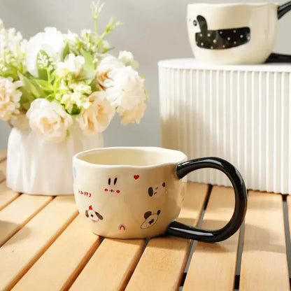 Cream-colored ceramic big ear cup with black handle and pastel cartoon big ear faces decorbites kitchen decor