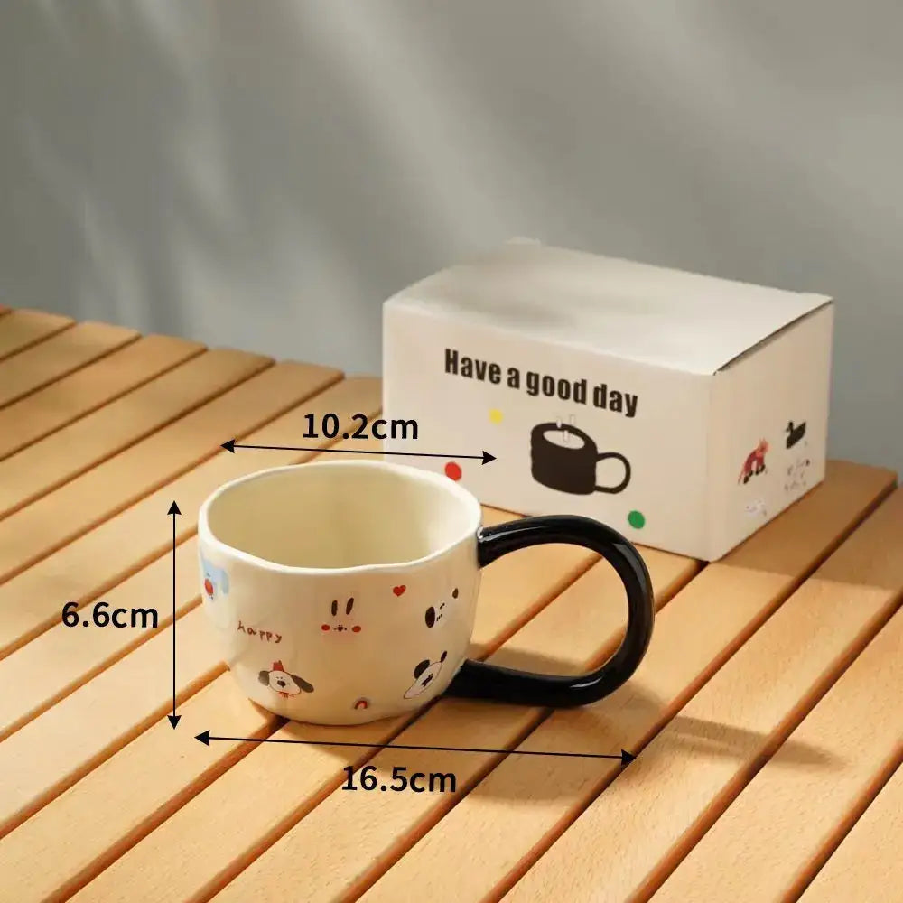 A white ceramic cartoon big ear cup with black handle and cute animal decals beside have a good day packaging