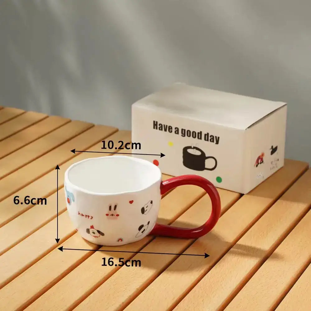 White ceramic mug with red handle featuring playful cartoon big ear dog illustrations beside decorbites cartoon big packaging
