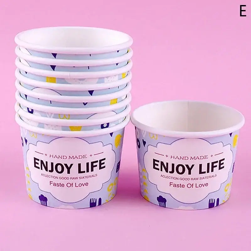 A stack of light purple decorbites cartoon paper cups with playful pattern and enjoy life print for dessert use