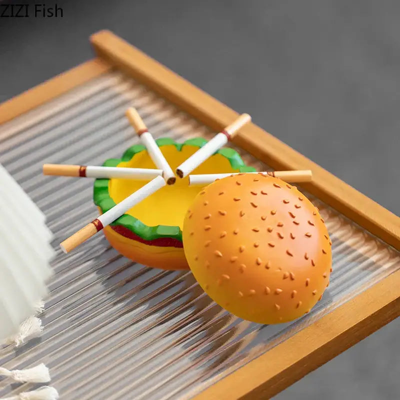 Orange resin cartoon burger ashtray shaped like a sesame seed bun with green lettuce and yellow patty details for office decor