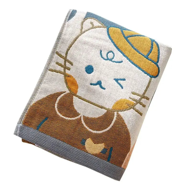 A cream-colored cotton gauze bath towel with an embroidered cat in a yellow hat and brown dress by decorbites