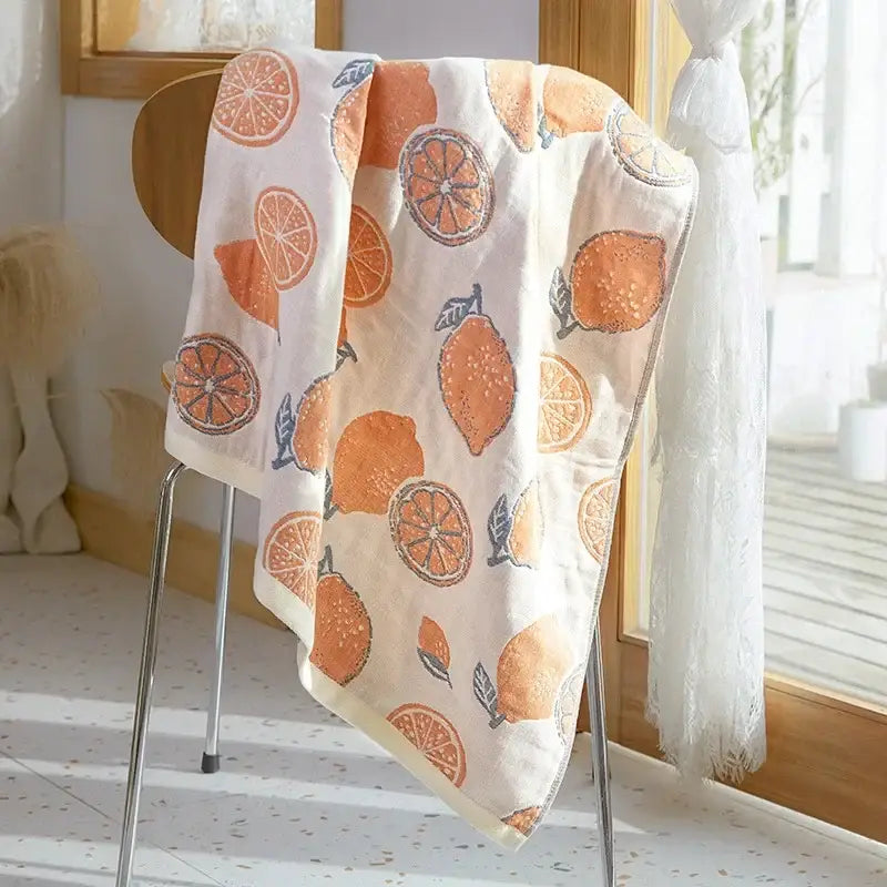 A soft off-white decorbites cotton gauze bath towel with orange slice and lemon pattern for bathroom use