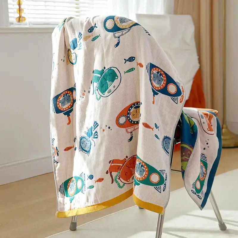A soft off-white decorbites cotton gauze bath towel with colorful cartoon submarines and fish pattern for bathroom use