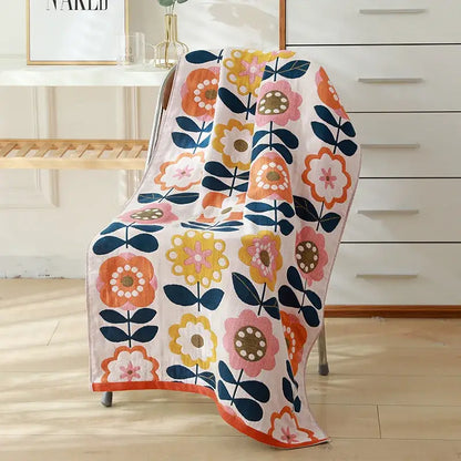 A soft white cotton gauze bath towel with vibrant orange pink yellow and navy blue floral pattern by decorbites