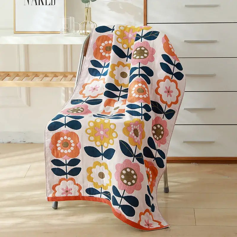 A soft white cotton gauze bath towel with vibrant orange pink yellow and navy blue floral pattern by decorbites