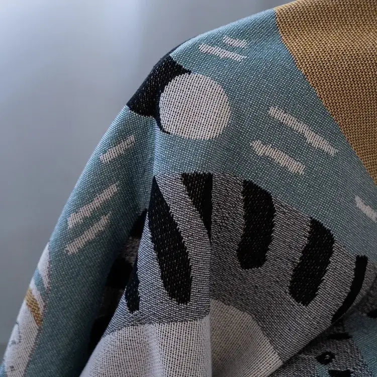 A soft textured cat throw blanket in muted teal black white and beige with a modern geometric pattern from decorbites cartoon cat collection