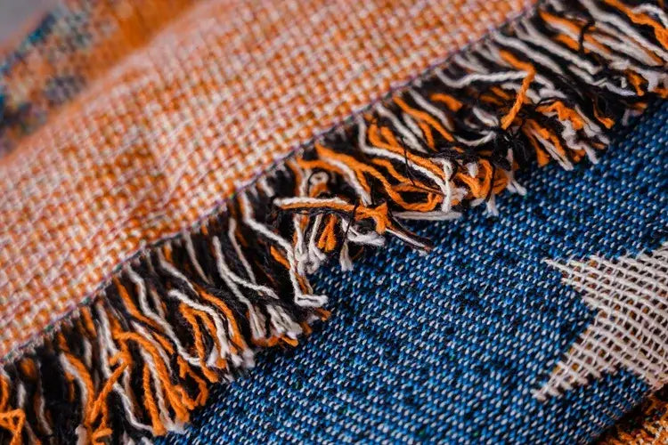 A textured decorbites cartoon cat throw blanket with woven orange and blue pattern and fringed edges for sofa decor