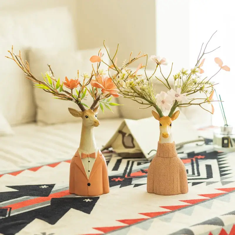 Two ceramic cartoon deer vases in orange tuxedo and beige dress holding floral antlers for living room decor