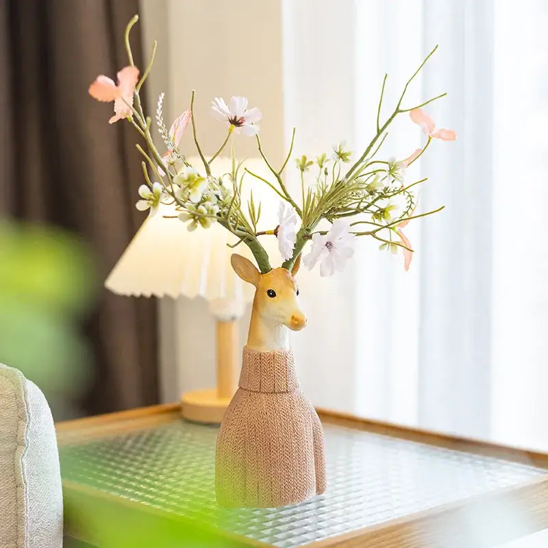 Beige knitted sweater cartoon deer vase with orange resin base holding pink and white flowers for living room decor