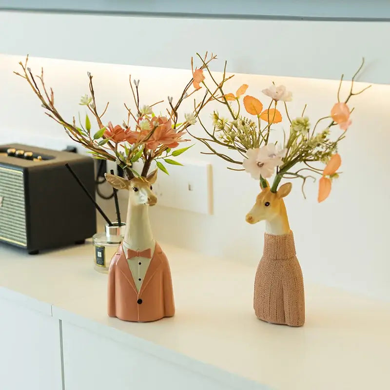 Two ceramic cartoon deer vases in beige and orange resin dressed with floral arrangements for living room decor